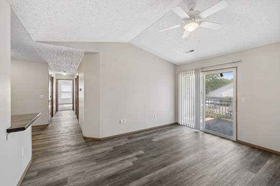 A spacious room with a ceiling fan and sliding glass doors leading to a patio.