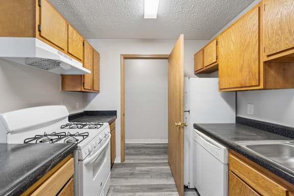 A kitchen with a white stove and wooden cabinets.