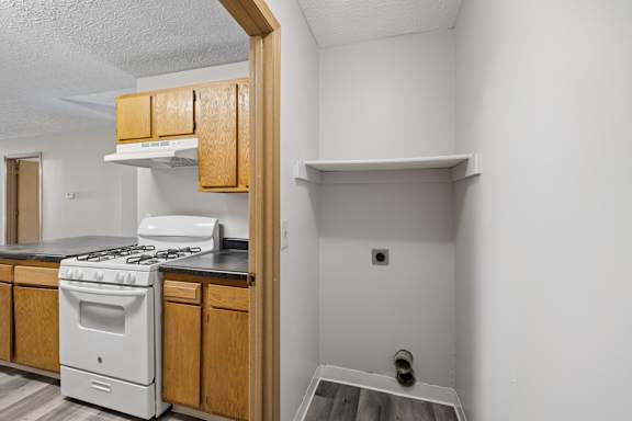 A white stove is in a kitchen with wooden cabinets.