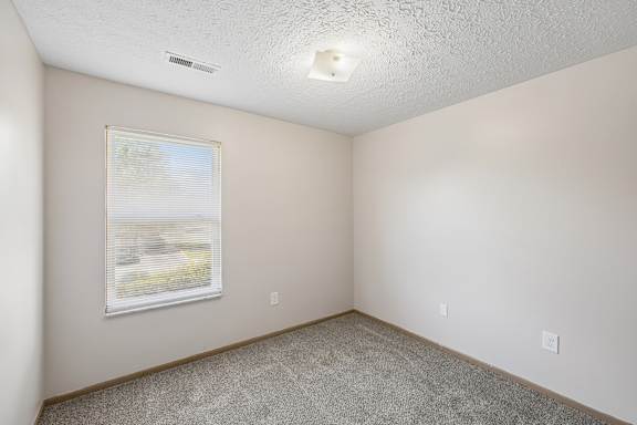 A room with a window and carpeted floor.