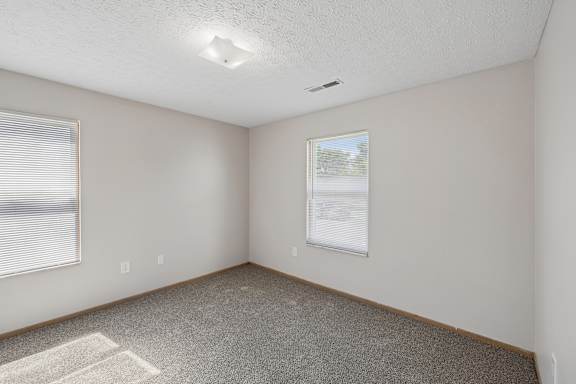 A room with a poster on the wall and a window with blinds.