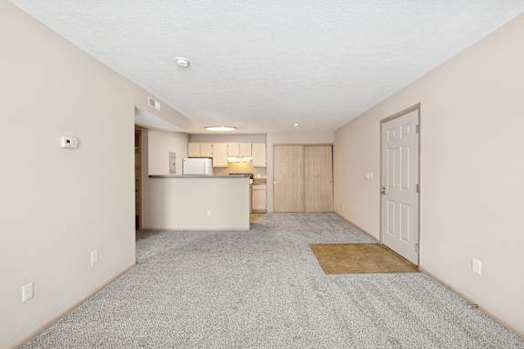 A spacious room with a kitchen in the background and a door on the right.