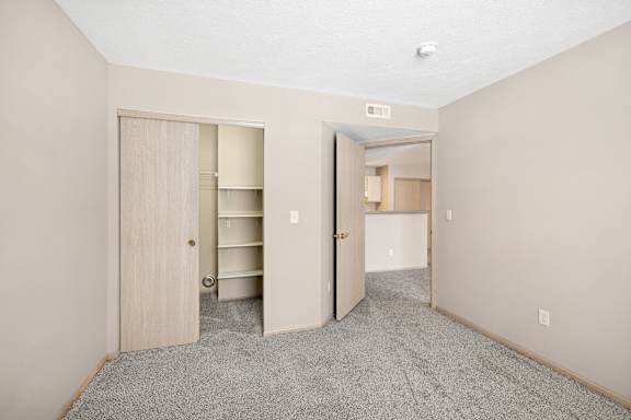 A room with a carpeted floor and two open doors.