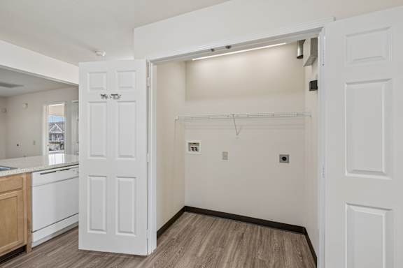 A white door is open to a room with a wooden floor.