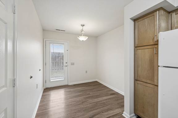 A room with a white door and a white fridge.