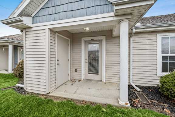 A house with a grey siding and a white door.