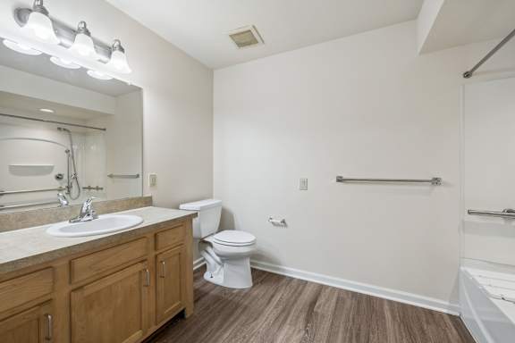 A bathroom with a white toilet and wooden floors.