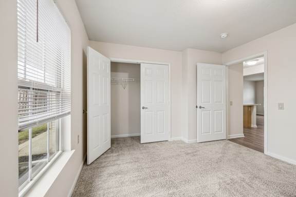 A room with white doors and carpeted floor.