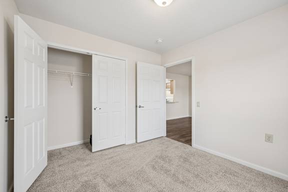 A room with white doors and carpeted floor.