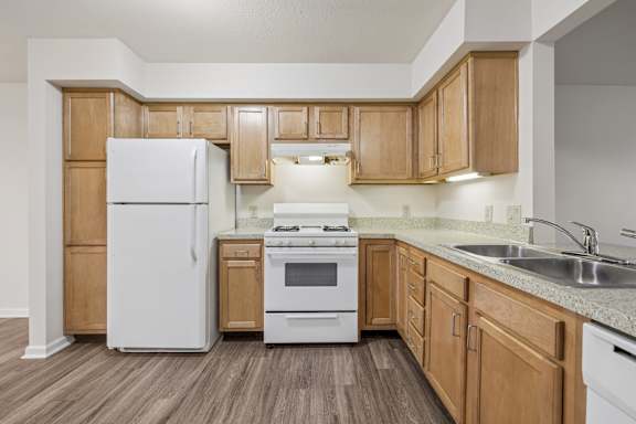 A kitchen with wooden cabinets and white appliances.