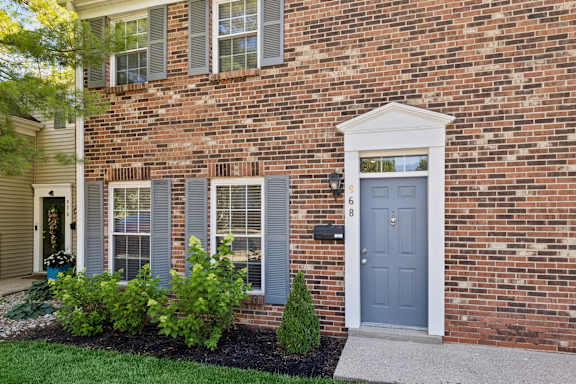A brick house with a blue door and a mailbox with the number 68 on it.