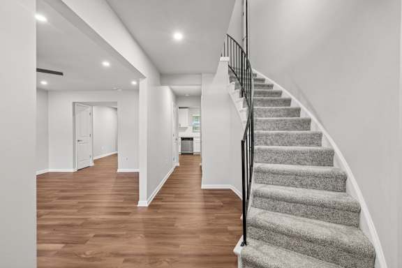 A staircase with a carpeted runner and a black railing.