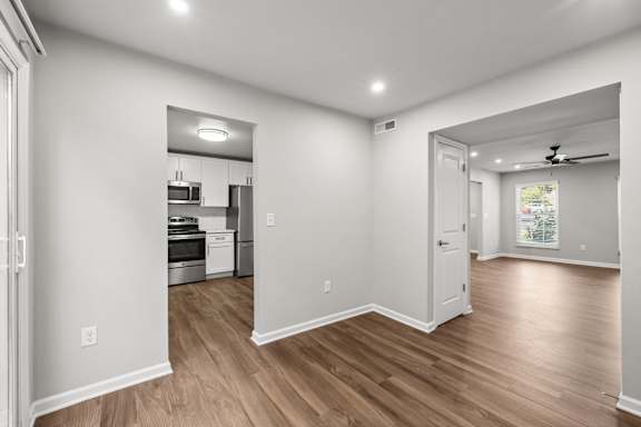 A spacious room with wooden floors and white walls.