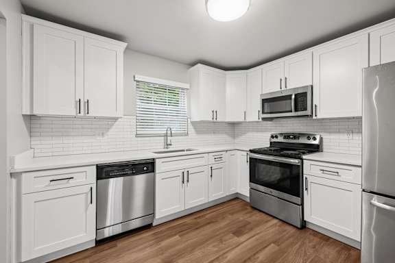 A kitchen with white cabinets and stainless steel appliances.