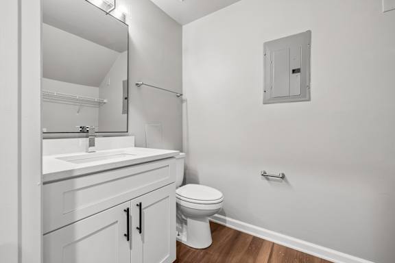 A white bathroom with a toilet, sink, and mirror.