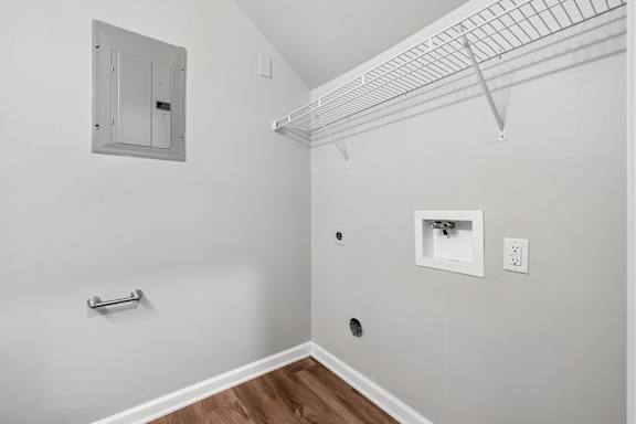 A white wall with a small white box and a white electrical outlet.