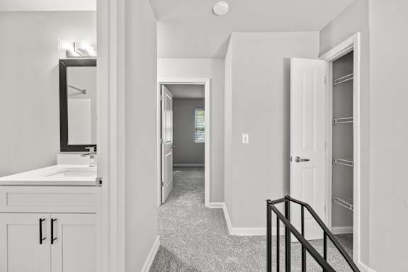 A bathroom with a sink, mirror, and a hallway.