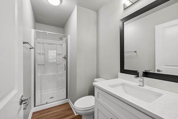 A white bathroom with a toilet, sink, and shower.