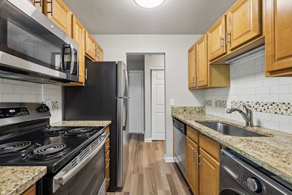 A kitchen with black appliances and wooden cabinets.