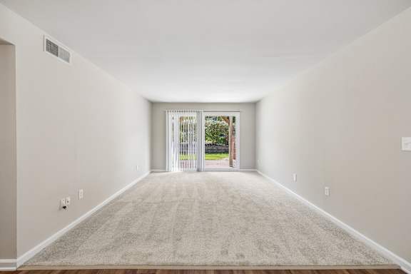 A room with a carpeted floor and a doorway leading to a balcony.