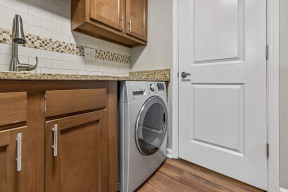 A washing machine is sitting in a kitchen next to a white door.