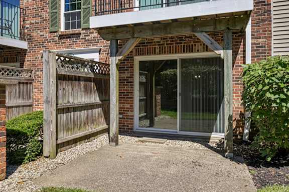 A wooden gate leads to a glass door entrance.