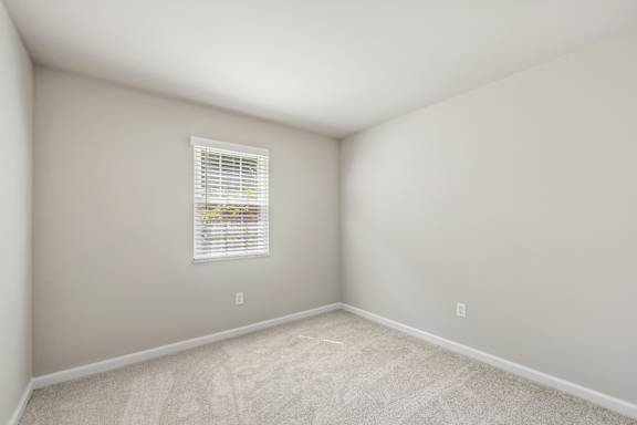 A room with a window and carpeted floor.