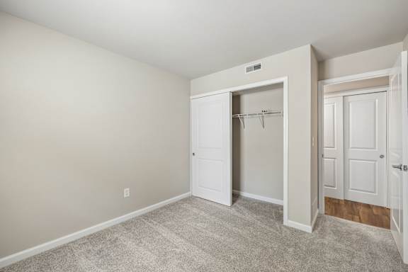 A room with a white door and a carpeted floor.