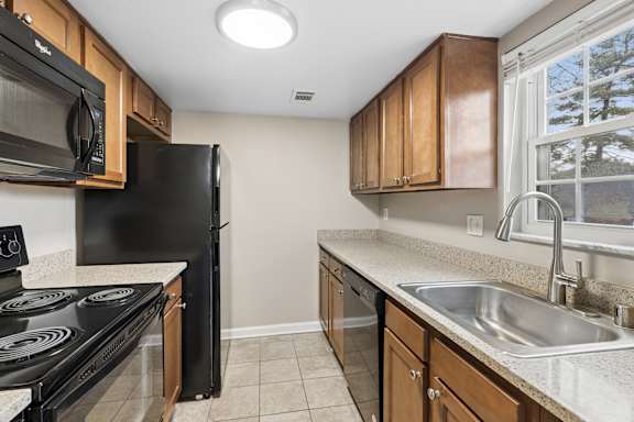 A kitchen with black appliances and brown cabinets.