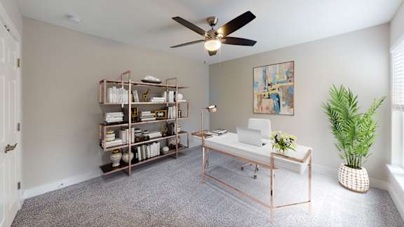 A room with a ceiling fan, a table with a plant, and a shelf with books and decorative items.