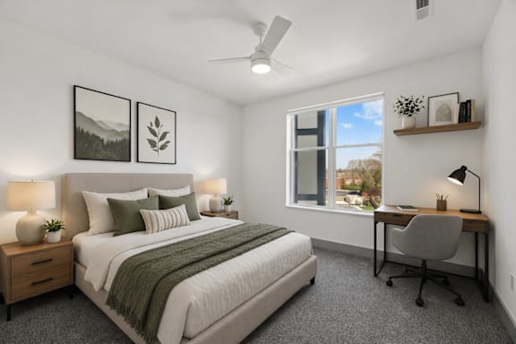 A bedroom with a bed, desk, and a window overlooking a cityscape.