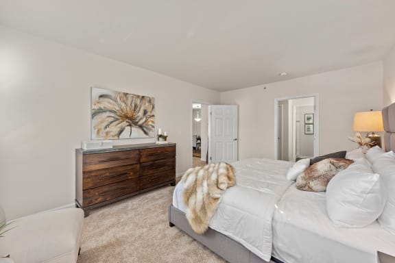a bedroom with a bed and a dresser and a door to a bathroom