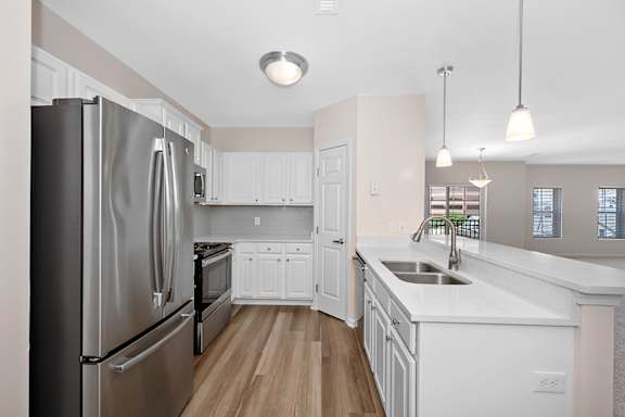 A kitchen with a stainless steel refrigerator and white cabinets. at Roebling Row, Covington, KY, 41011-1720