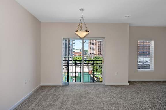 A room with a carpet floor, a window with blinds, and a door leading to a balcony. at Roebling Row, Covington, Kentucky