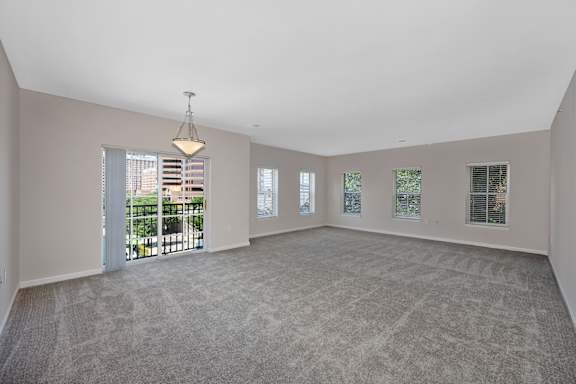 A spacious room with a carpeted floor and a large window with a view of a balcony. at Roebling Row, Covington, KY, 41011-1720