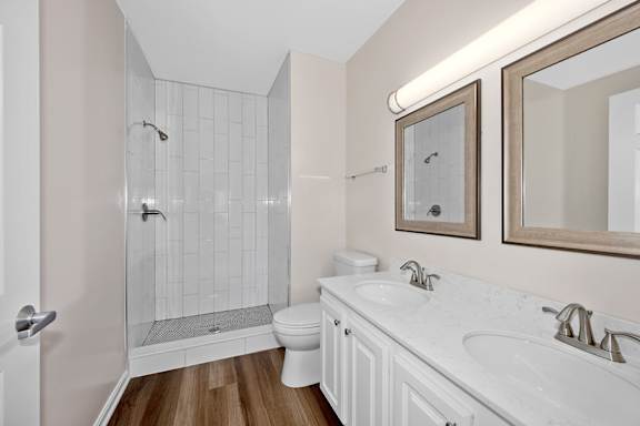 A white bathroom with a toilet, sink, and shower. at Roebling Row, Covington, KY