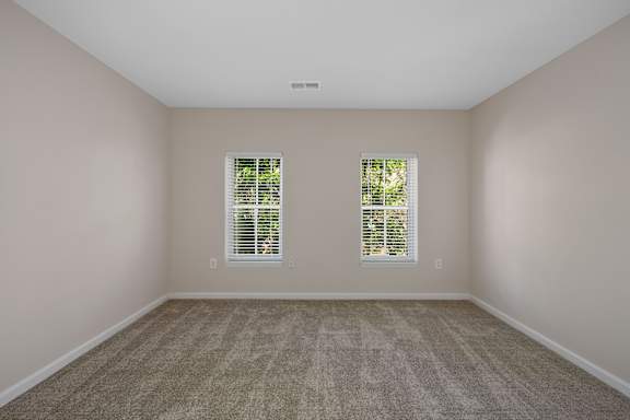 A room with carpeted floor and two windows with blinds. at Roebling Row, Covington, KY