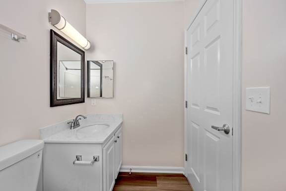 A white bathroom with a sink, mirror and toilet. at Roebling Row, Covington