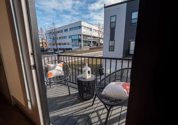 A balcony with a table and chairs overlooking a building.