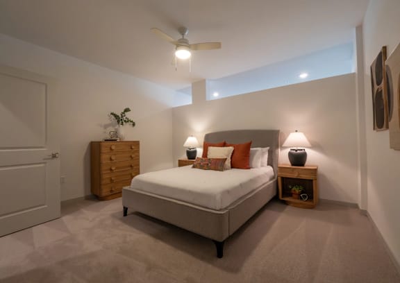 A bedroom with a bed, nightstand, and a ceiling fan.