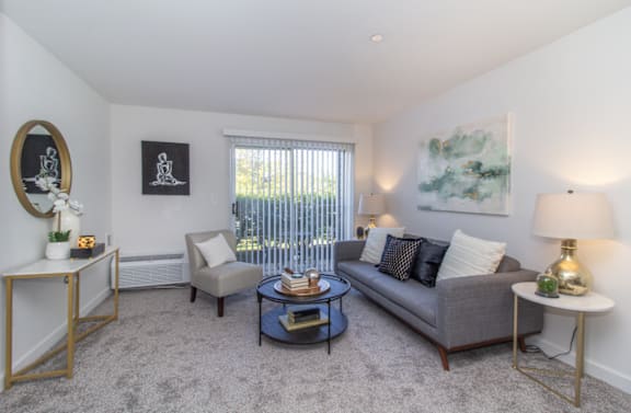 A living room with a grey couch, a coffee table, and a painting on the wall.
