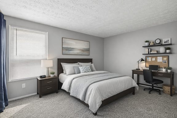A bedroom with a bed, desk, and chair.