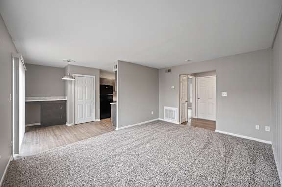 A large, empty room with a grey carpet and white walls.