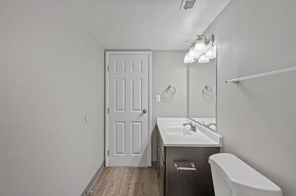 A white bathroom with a sink, mirror, and toilet.