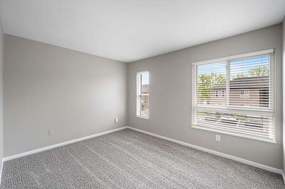 A room with a carpeted floor and a window with blinds.