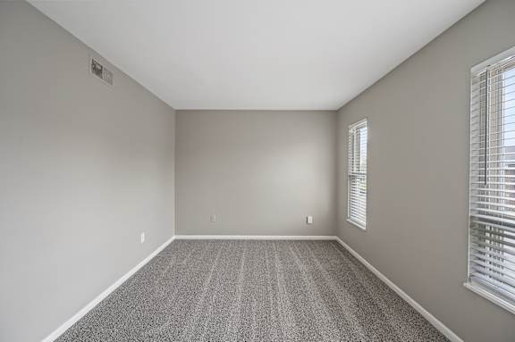 A room with a carpeted floor and a window with blinds.