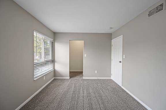 A room with a carpeted floor and a door in the middle.