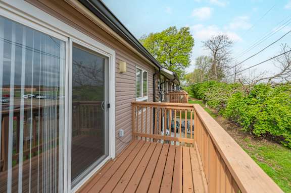 A wooden deck with a glass door leading to a patio.