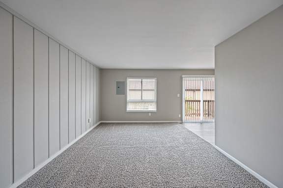 A room with a carpeted floor and a window with blinds.