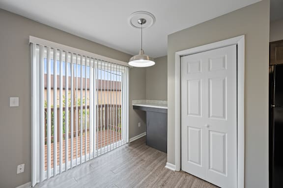 A kitchen area with a white door and a window with blinds.